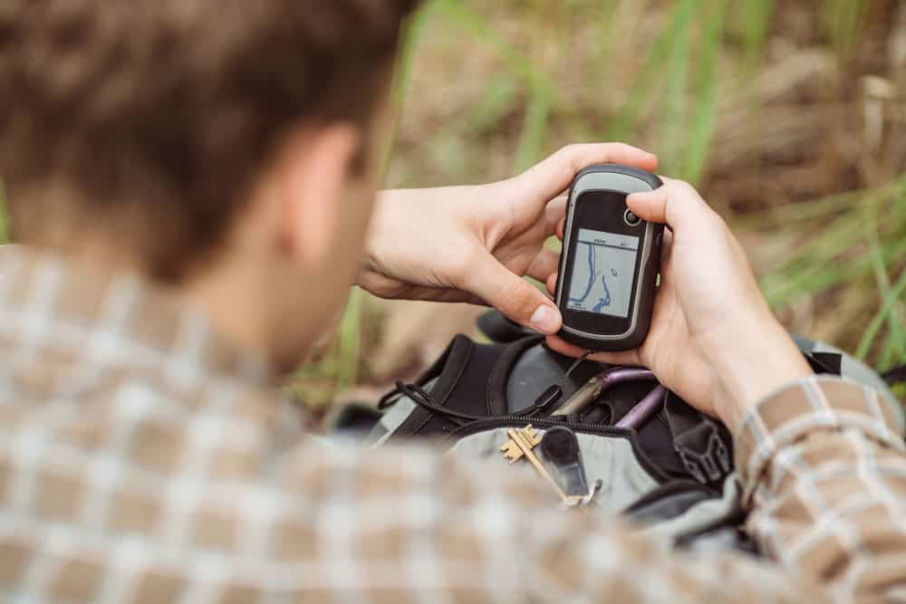 Young tourist in the woods determines location using GPS