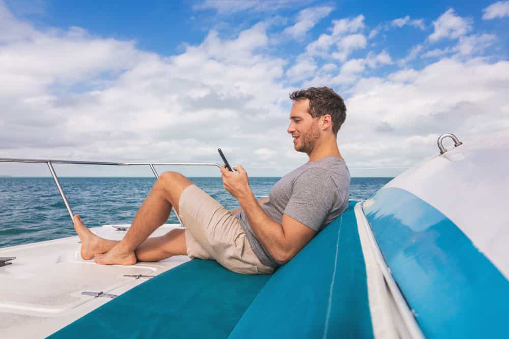 Yacht guy texting on satellite internet while relaxing