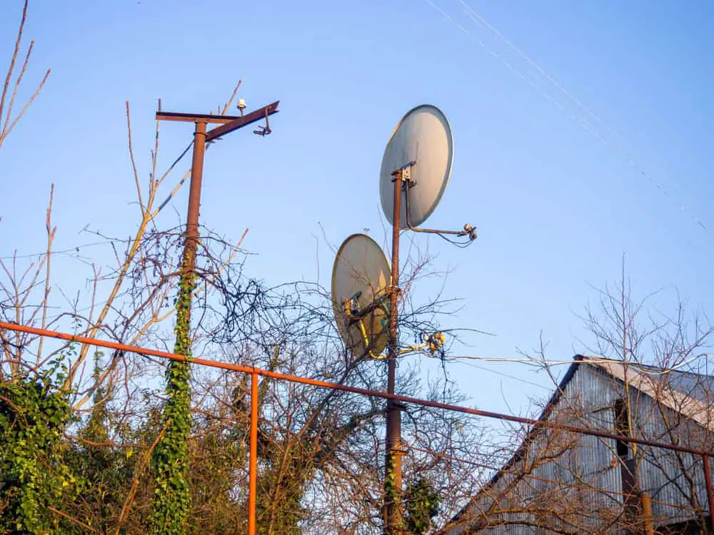Satellite dishes on a pole near a house