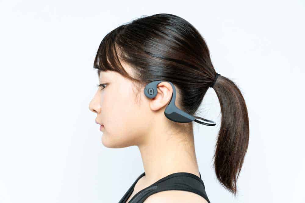A woman wearing bone-conduction headphones