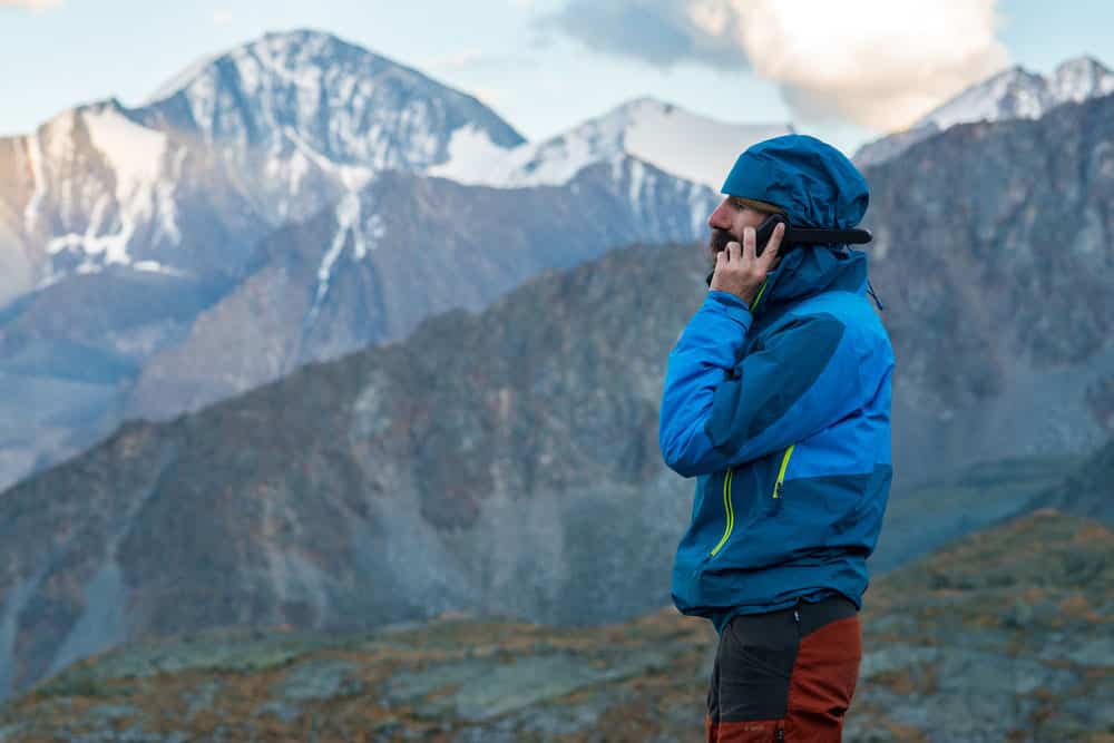 Man in the mountains talking on a satellite phone