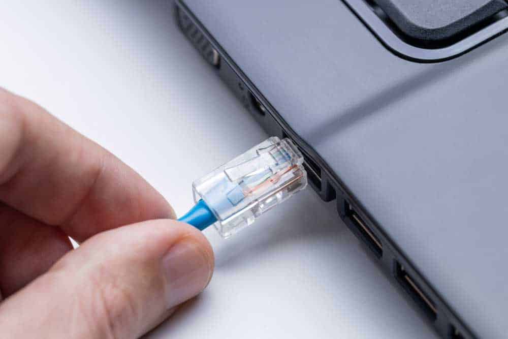 A person plugging an ethernet cable into a laptop