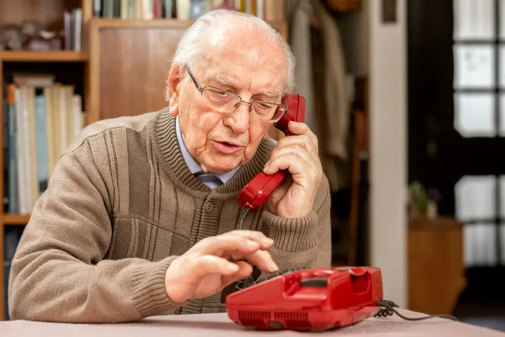 an older man uses a landline phone. 