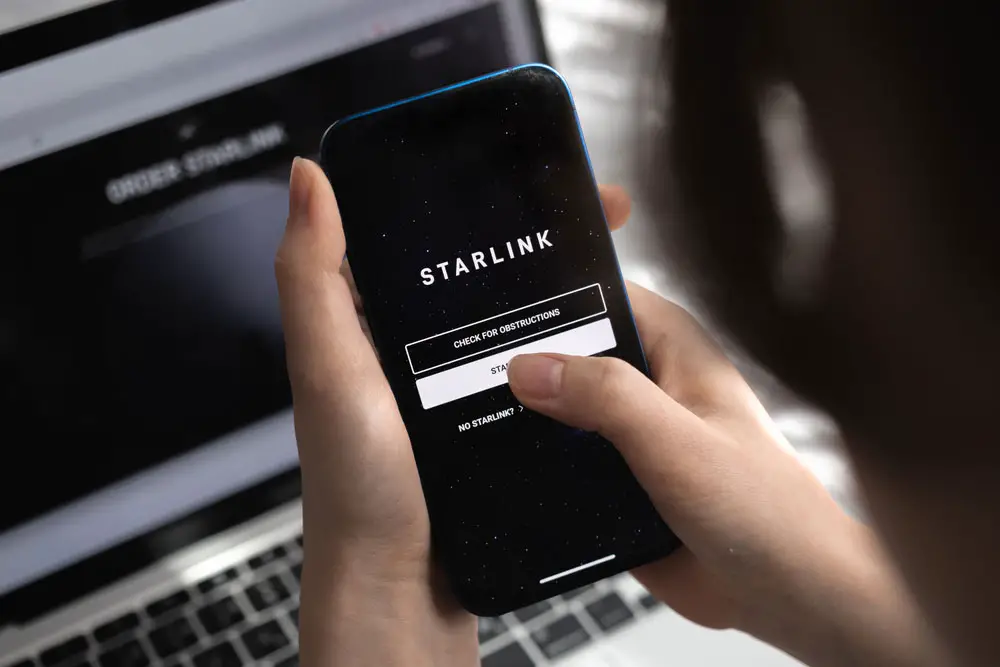 Woman uses a phone near a rectangular Starlink dish