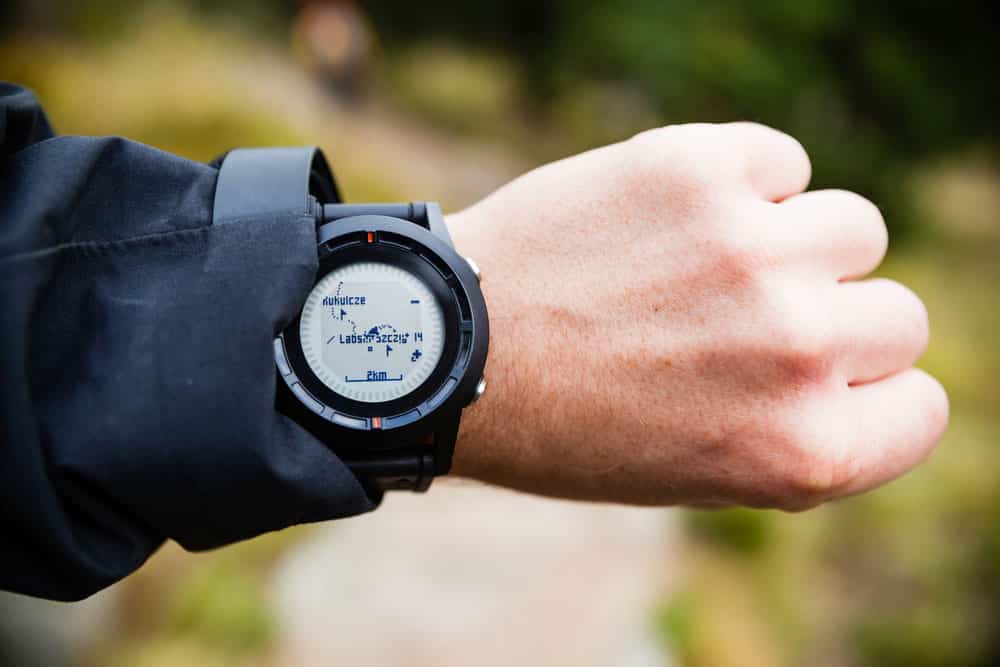 Hiker on mountain trail looking at GPS stopwatch