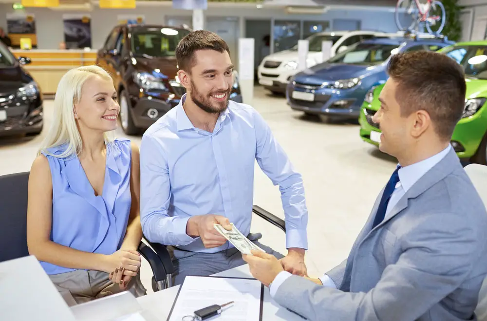 Happy couple talking to car dealer