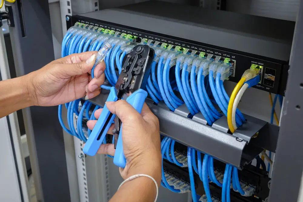 A network engineer holding an ethernet cable to connect to a server in a data center
