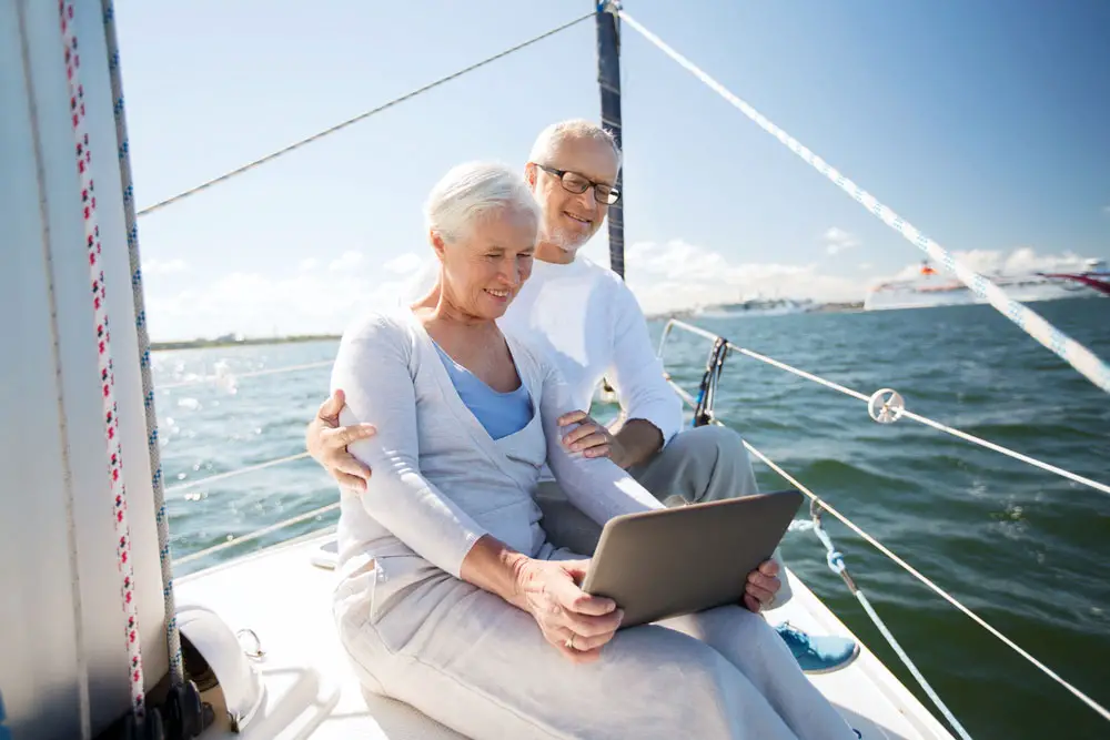 An old couple enjoys the internet on a yacht. 