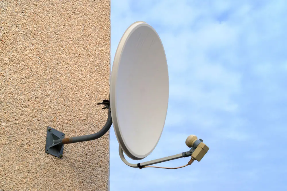 A satellite dish mounted on a wall using a J mount