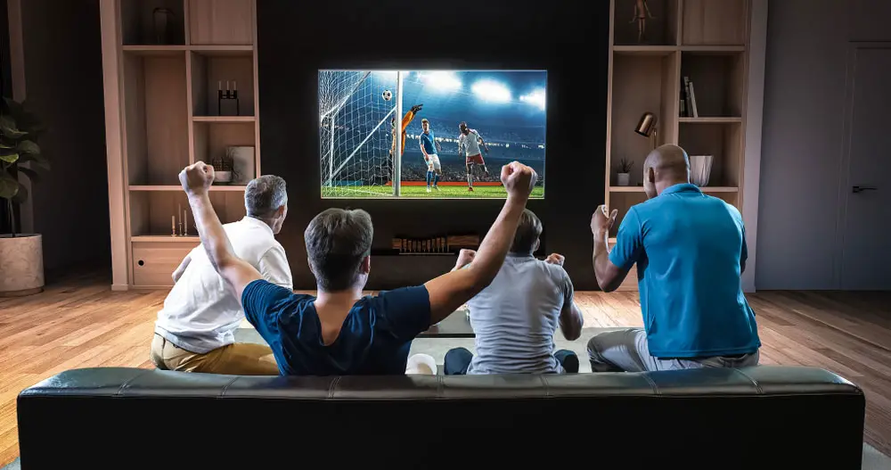 A group of men watching soccer on TV. 