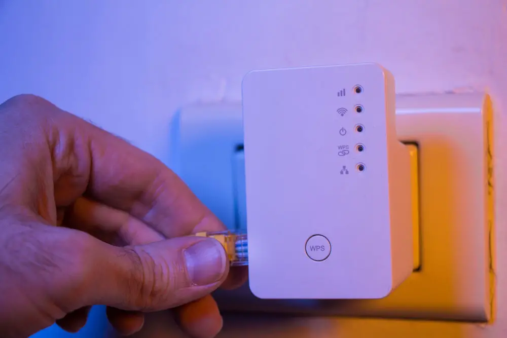 Man inserts ethernet cable into a WiFi extender