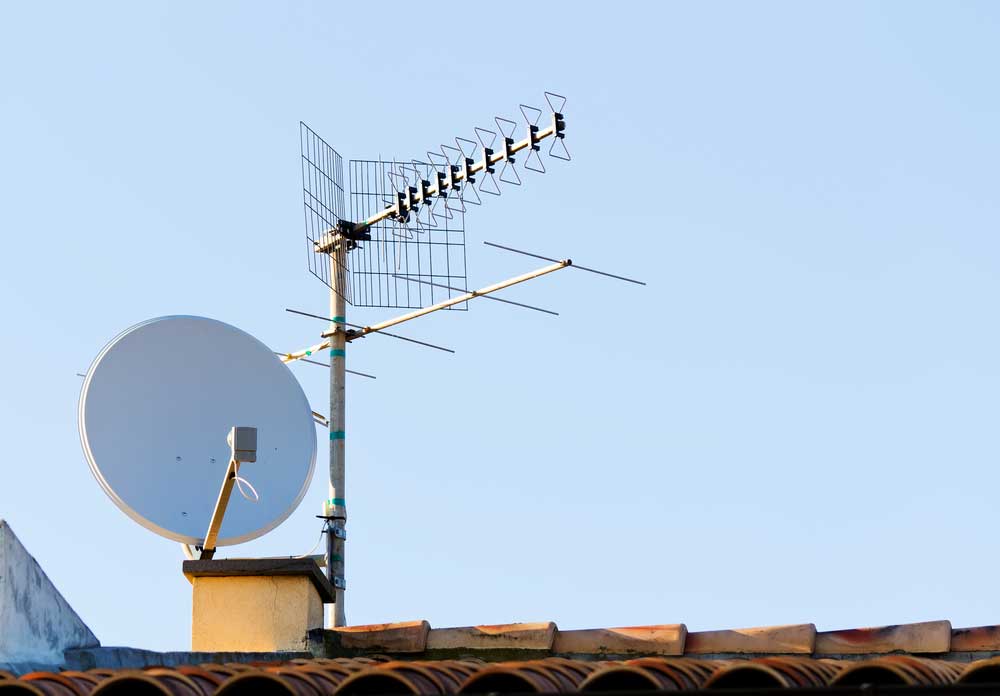 A satellite dish beside a TV antenna
