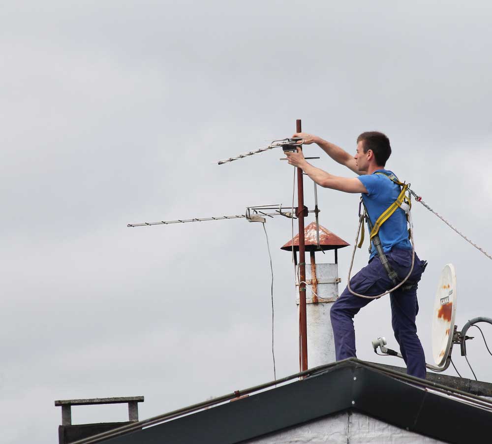 A worker installing an antenna on a roof