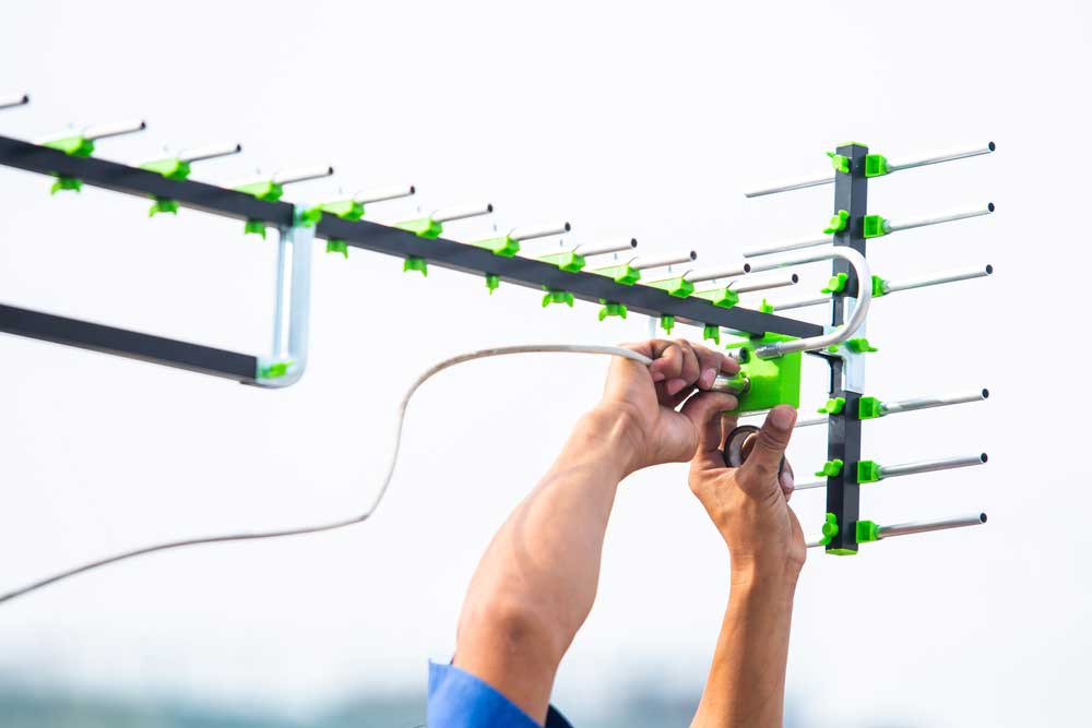 A persona adjusting a digital TV antenna