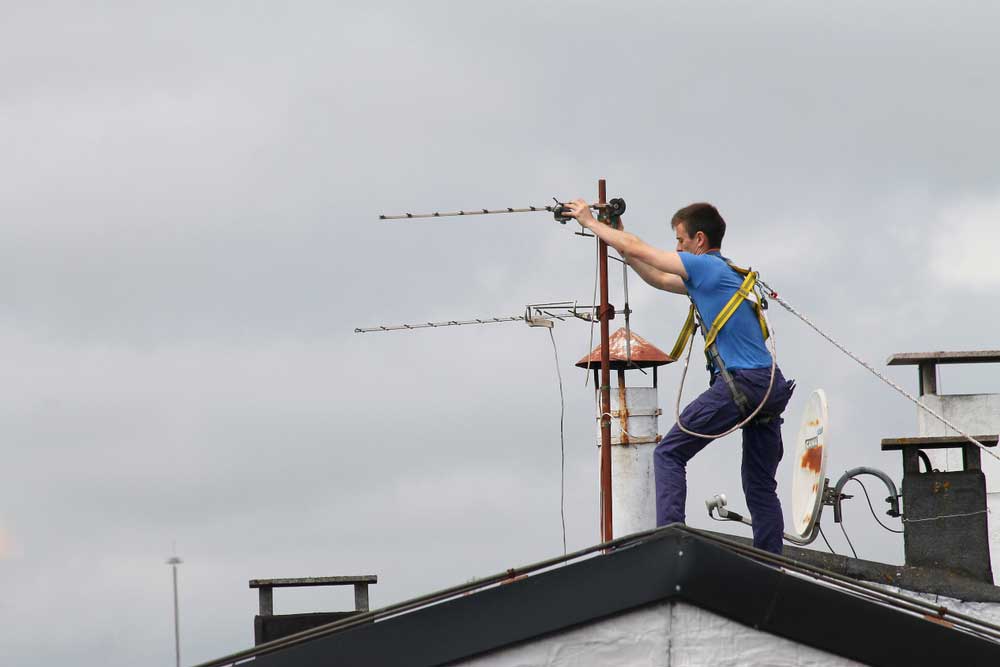 A person handling an antenna on the roof