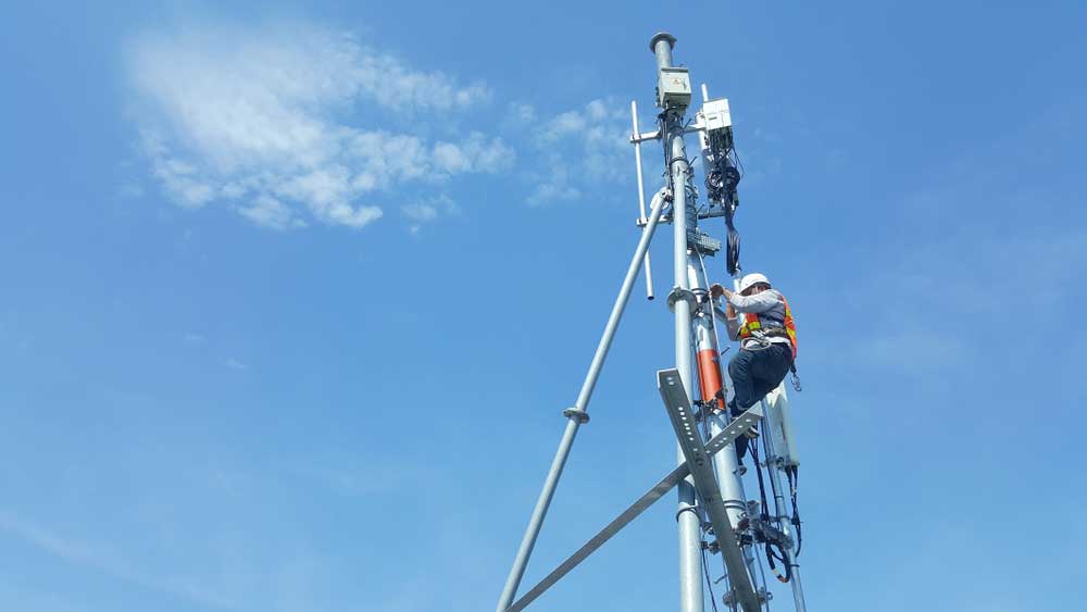 A man working on a high tower pole