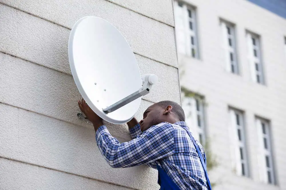 A young man fitting a satellite dish